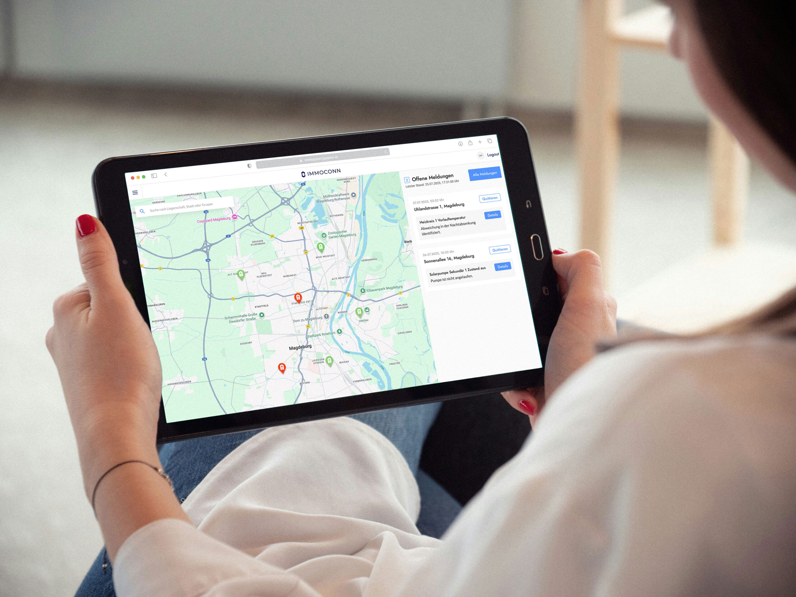 Frau hält ein Tablet in den Händen, auf dem eine Karte mit Markierungen und der Weboberfläche von IMMOCONN angezeigt wird.